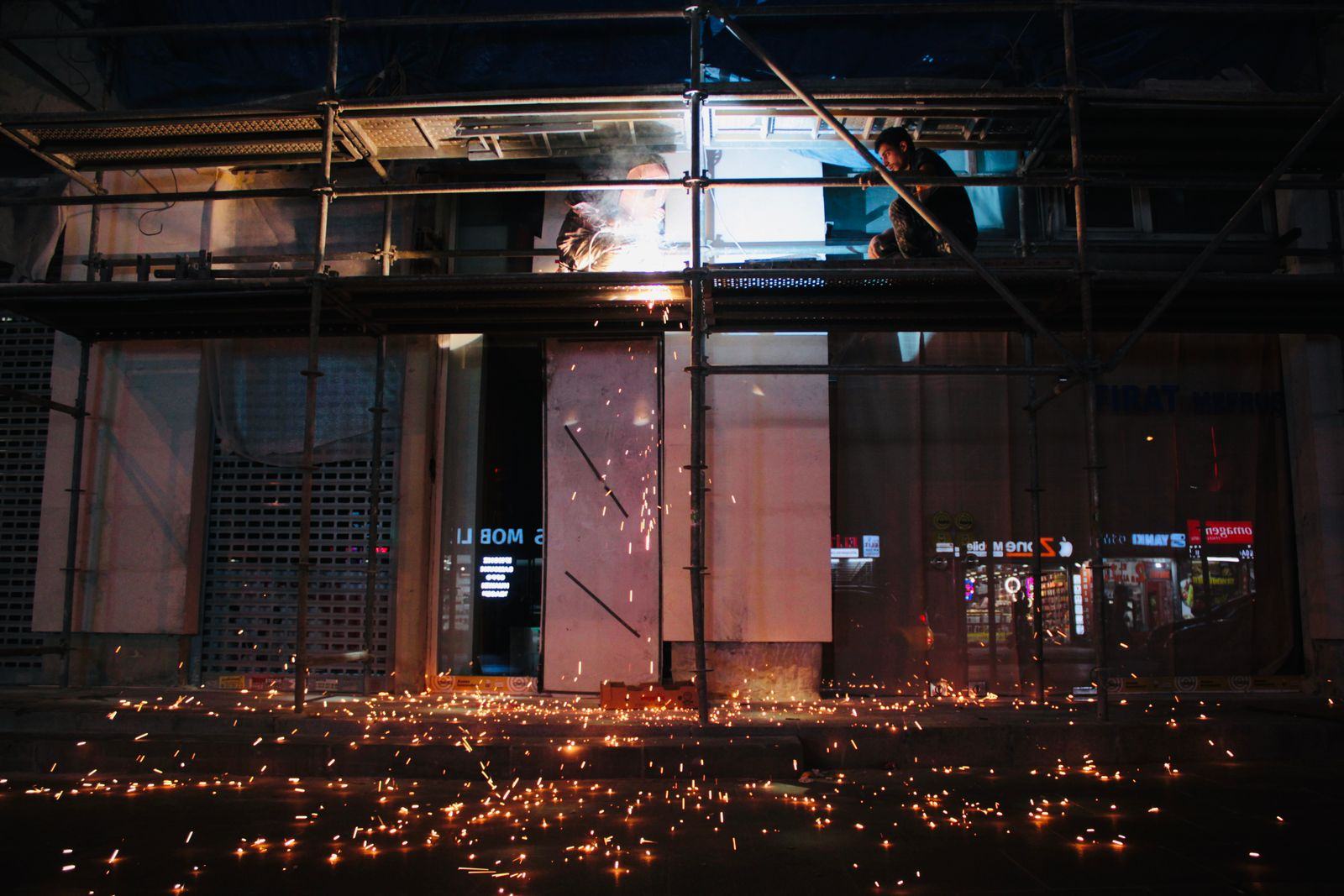 Welding sparks during hot work on a construction site at night, a common reason for fire watch